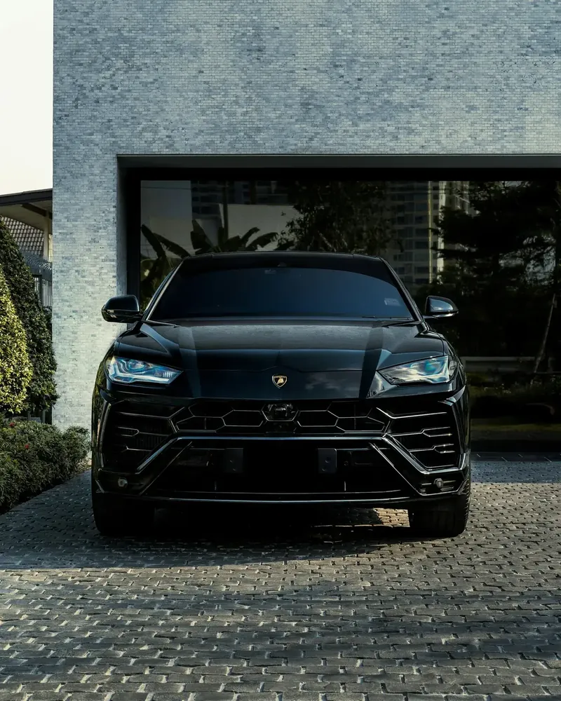 Lamborghini Urus noire devant un garage contemporain